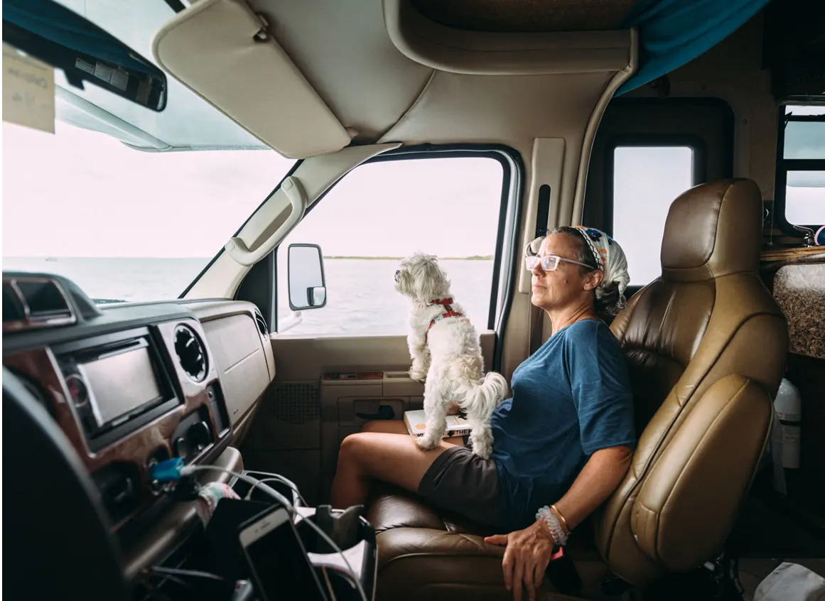 Woman and dog in RV by the sea.